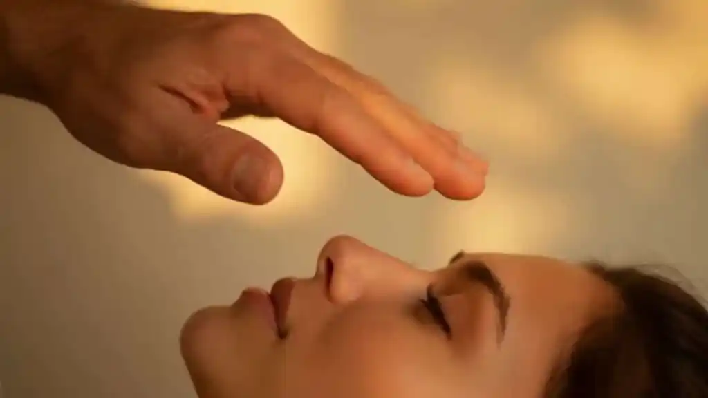 Application of medical qigong Doc Blackstone's hand hovering over the face of a female patient